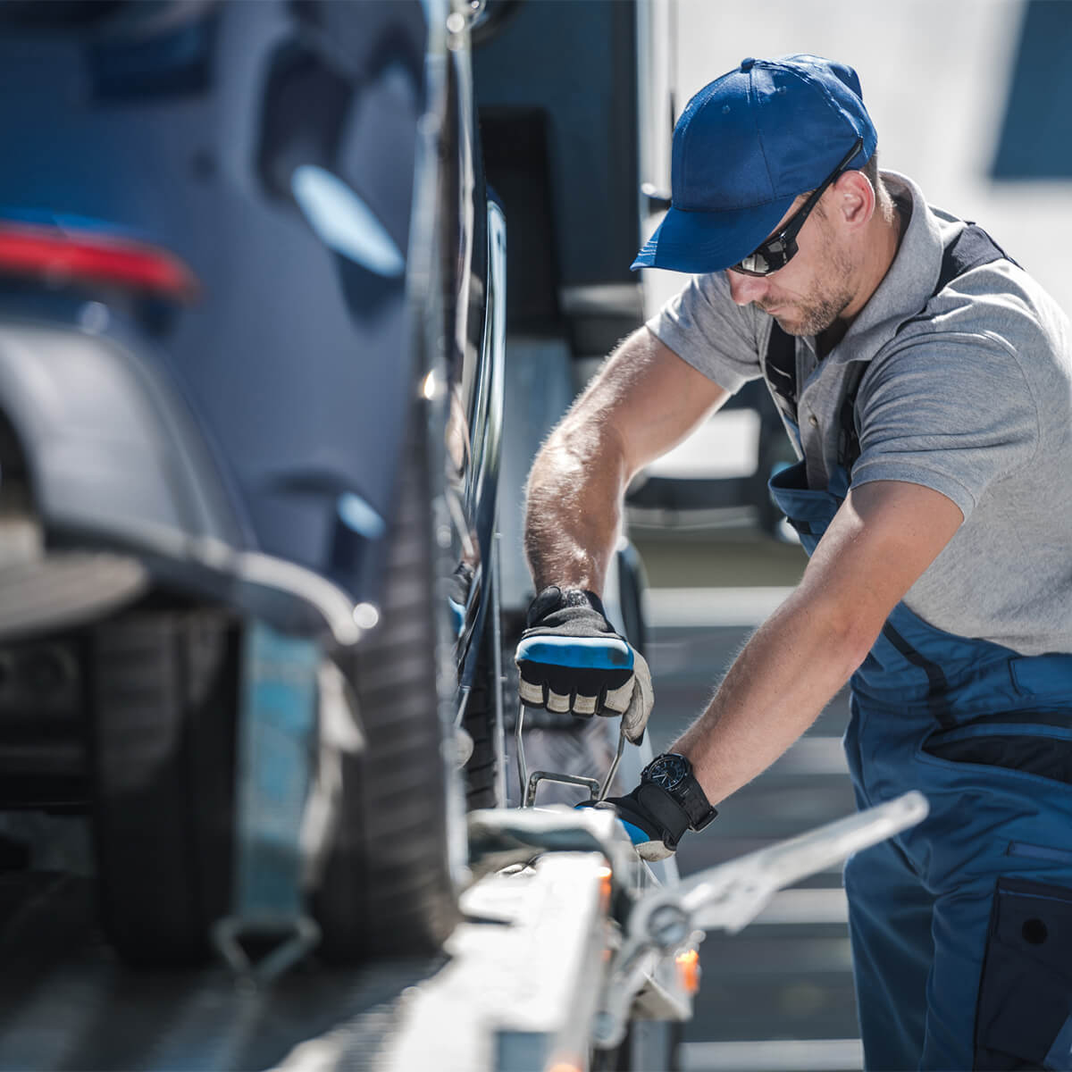 A man attaches a vehicle to a truck as part of a car repossession.