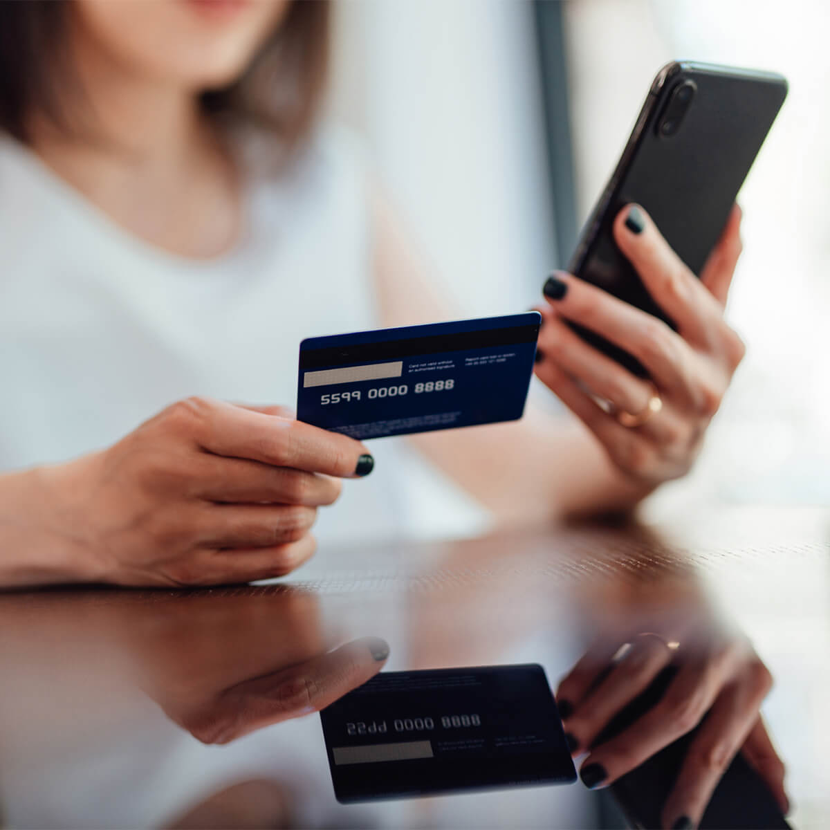 Une femme tient une carte de crédit et un téléphone dans ses mains