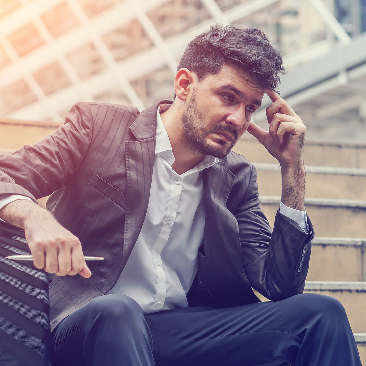 Un homme assis sur des escaliers l'air stressé
