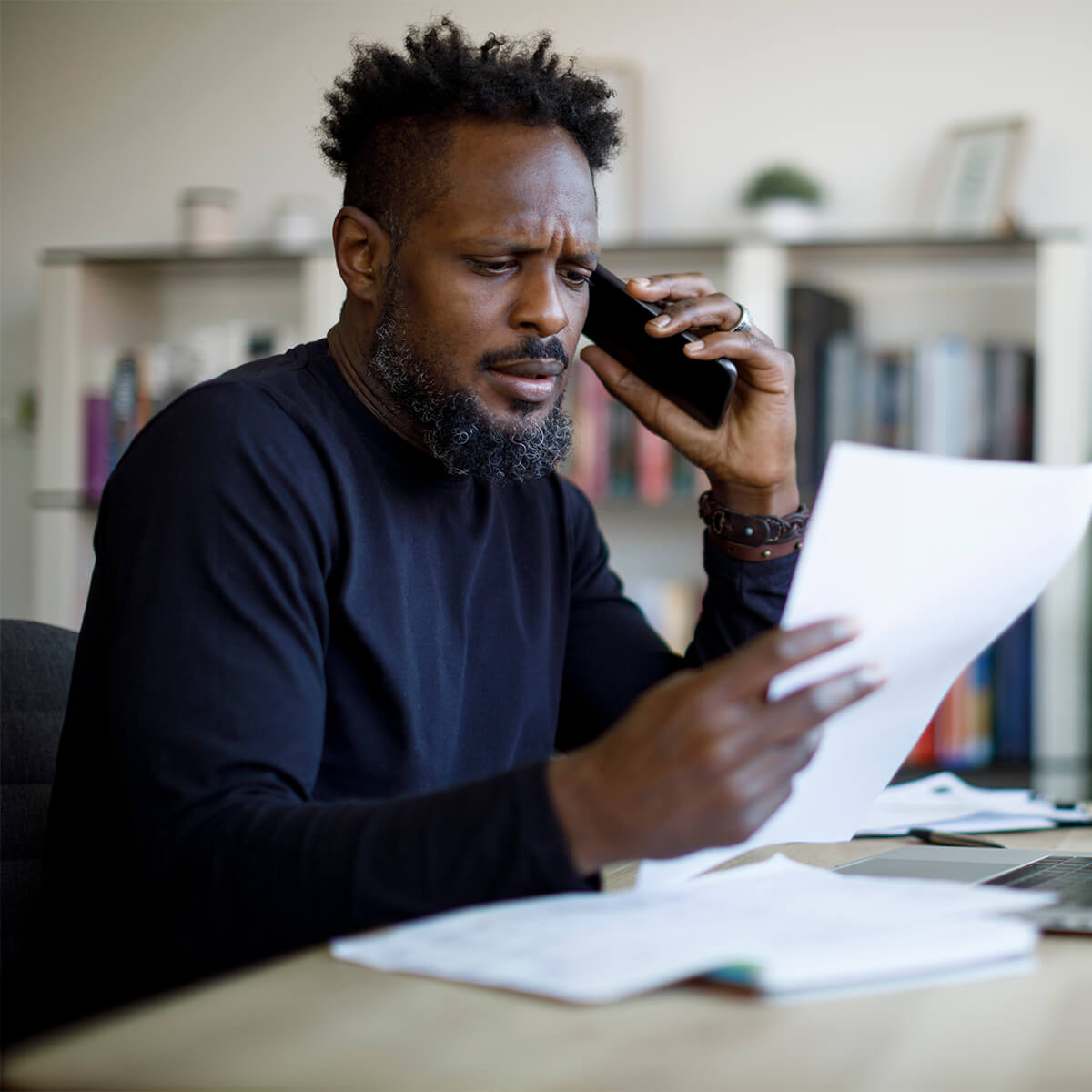 A man talking on the phone reads bills
