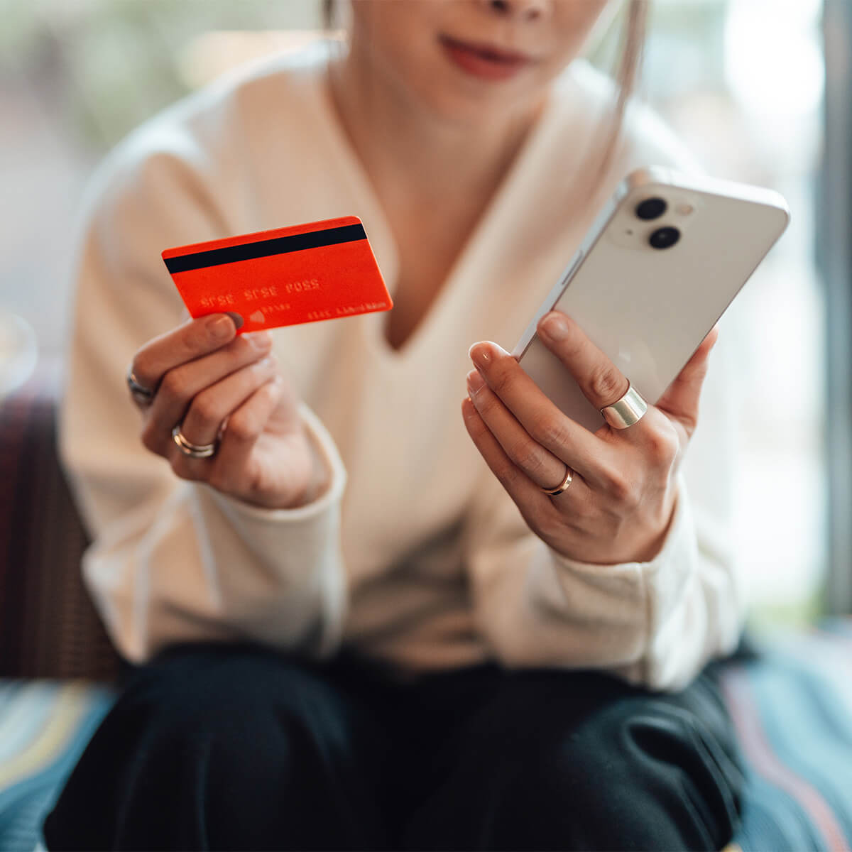 A woman holds a credit card and her phone