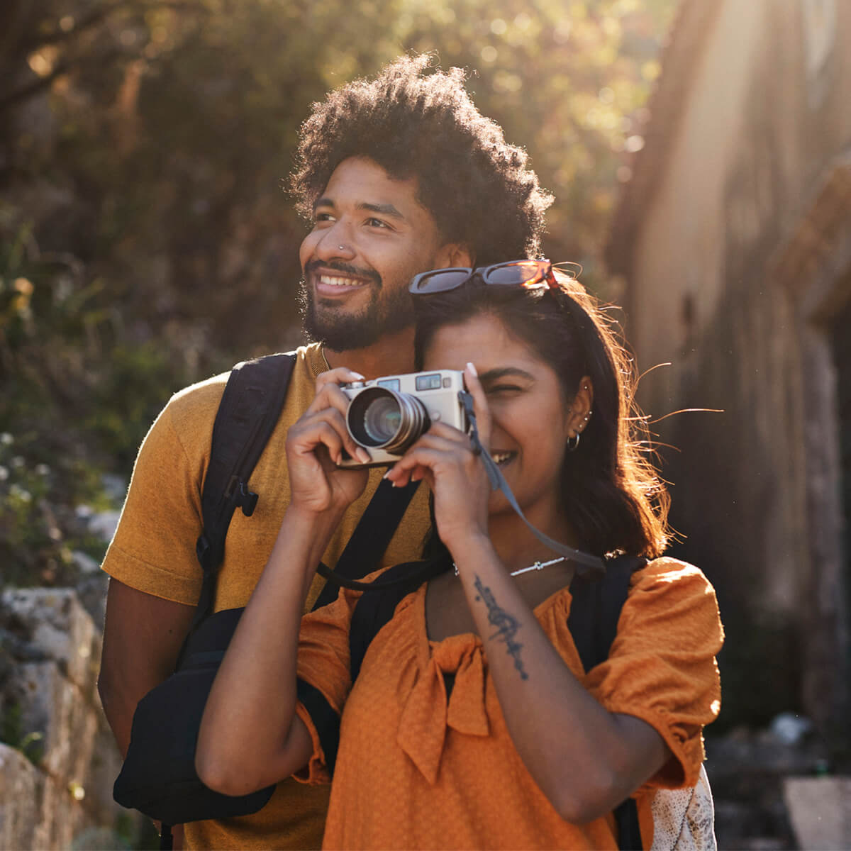 Young woman photographing through camera by boyfriend on sunny day during vacation