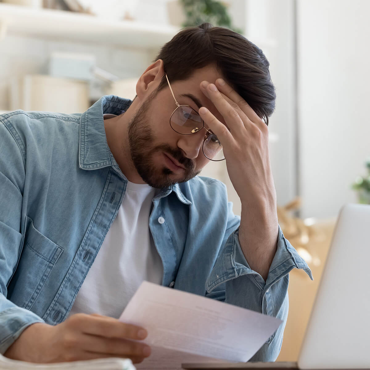 Frustrated young man reading a letter - stock photo