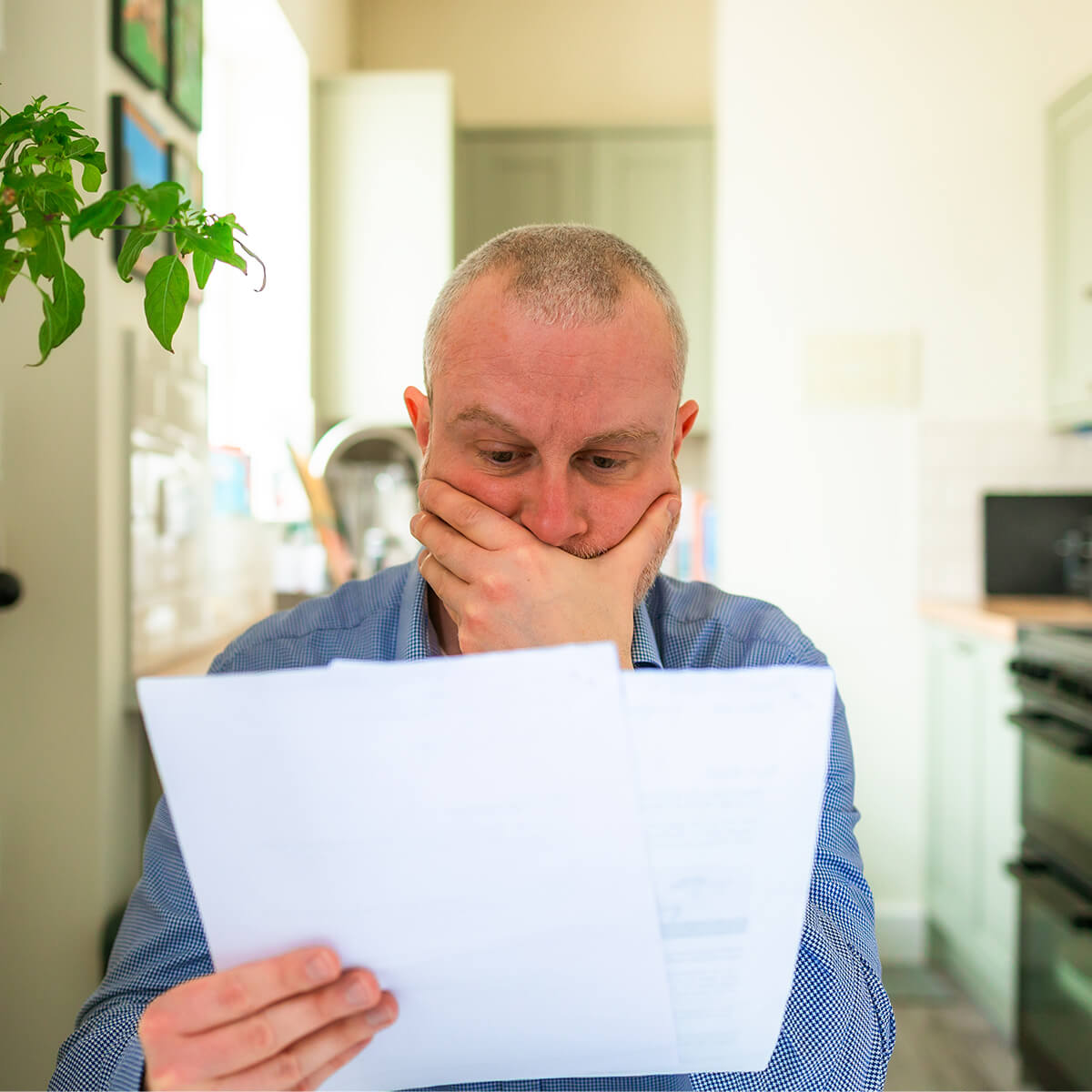 Homme lisant une lettre à la maison, l'air préoccupé