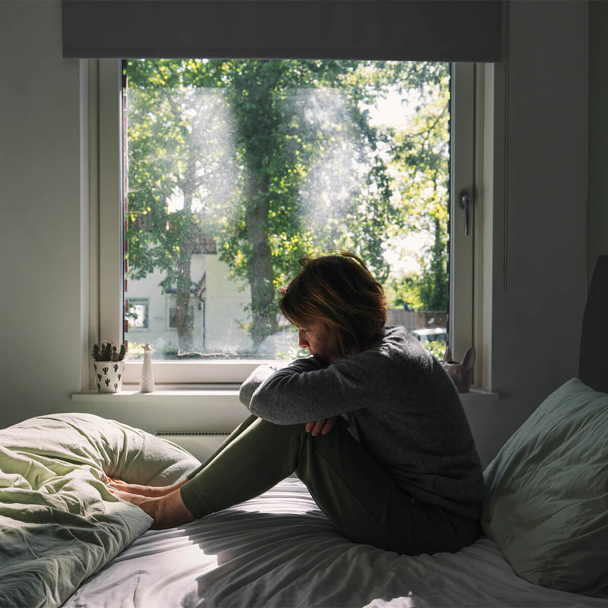 Woman sitting on her bed in contemplation