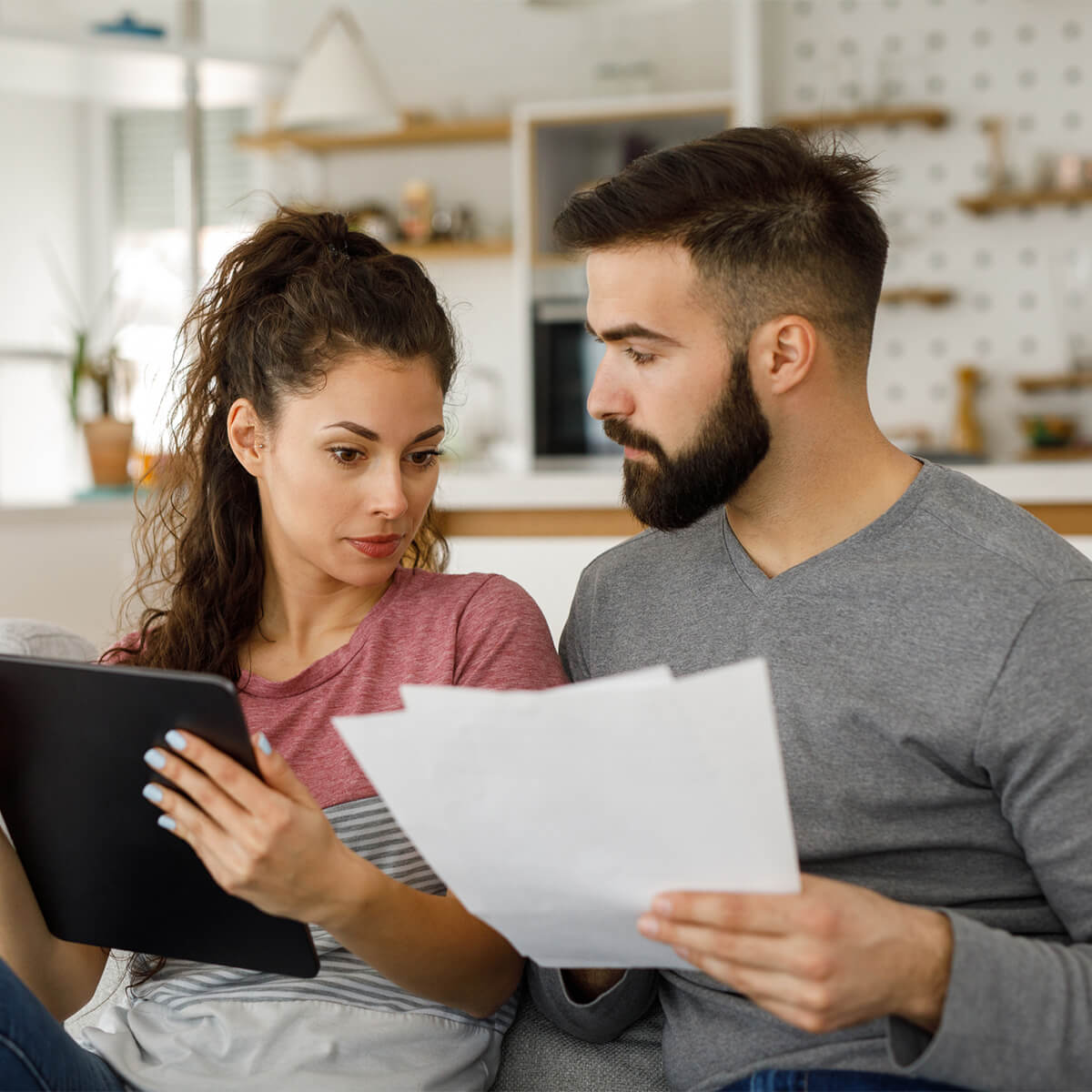 Young couple going over their finances together at home using digital tablet