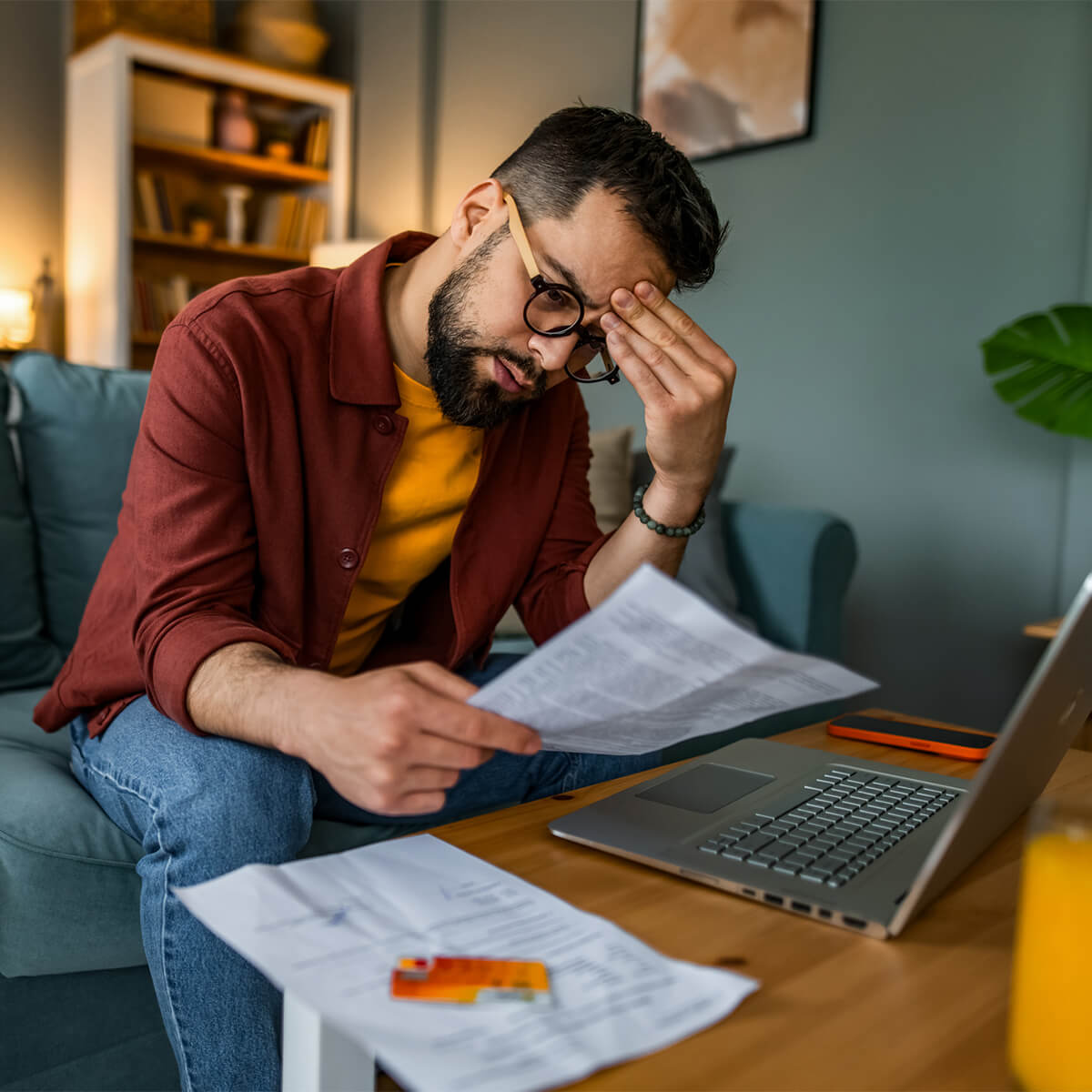Worried man managing budget and paying bills at home.