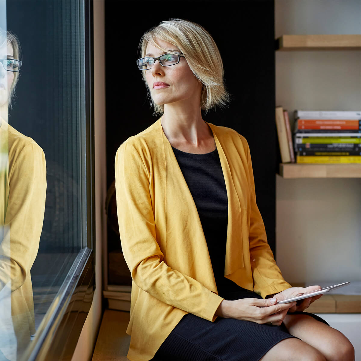 Business woman with a tablet, sitting in contemplation in an office