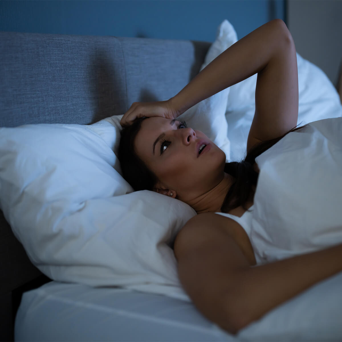 Young woman in bed alone, worried and contemplating