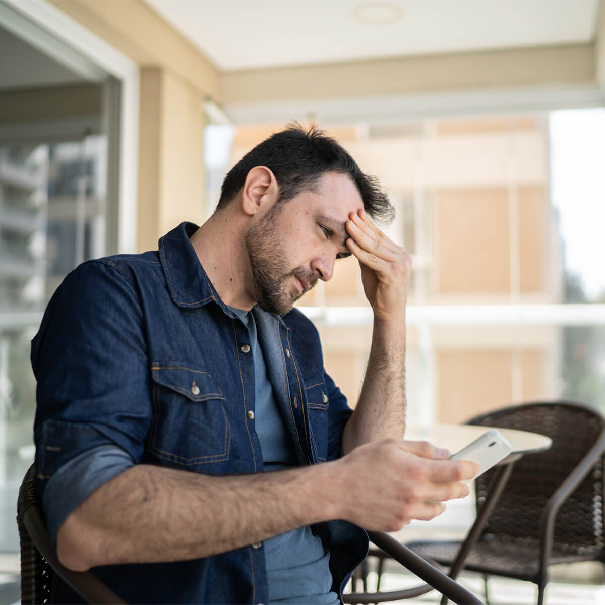 Man staring at phone and holding head after financial regret