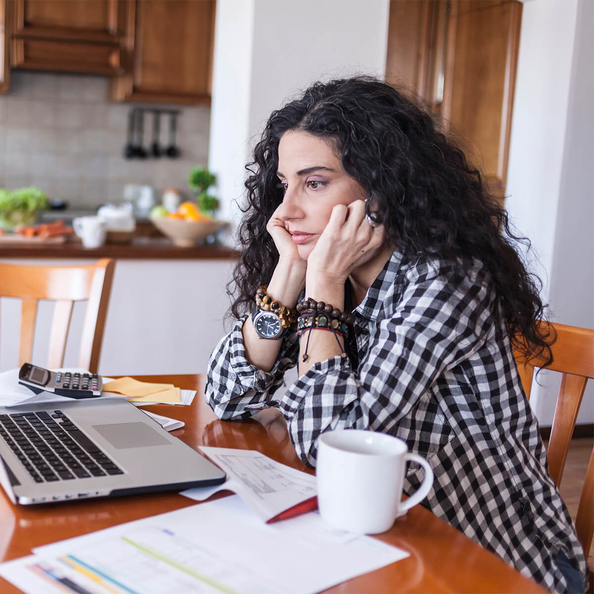 Une femme regarde son ordinateur en se tenant le visage à deux mains