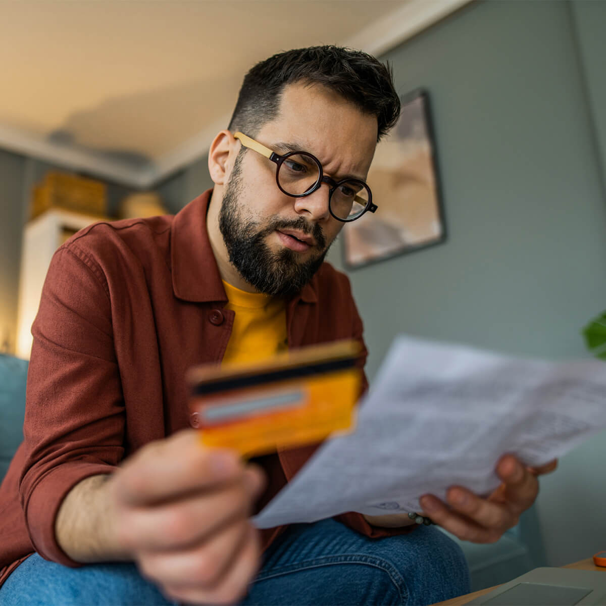 A man holds a credit card while looking at a bill