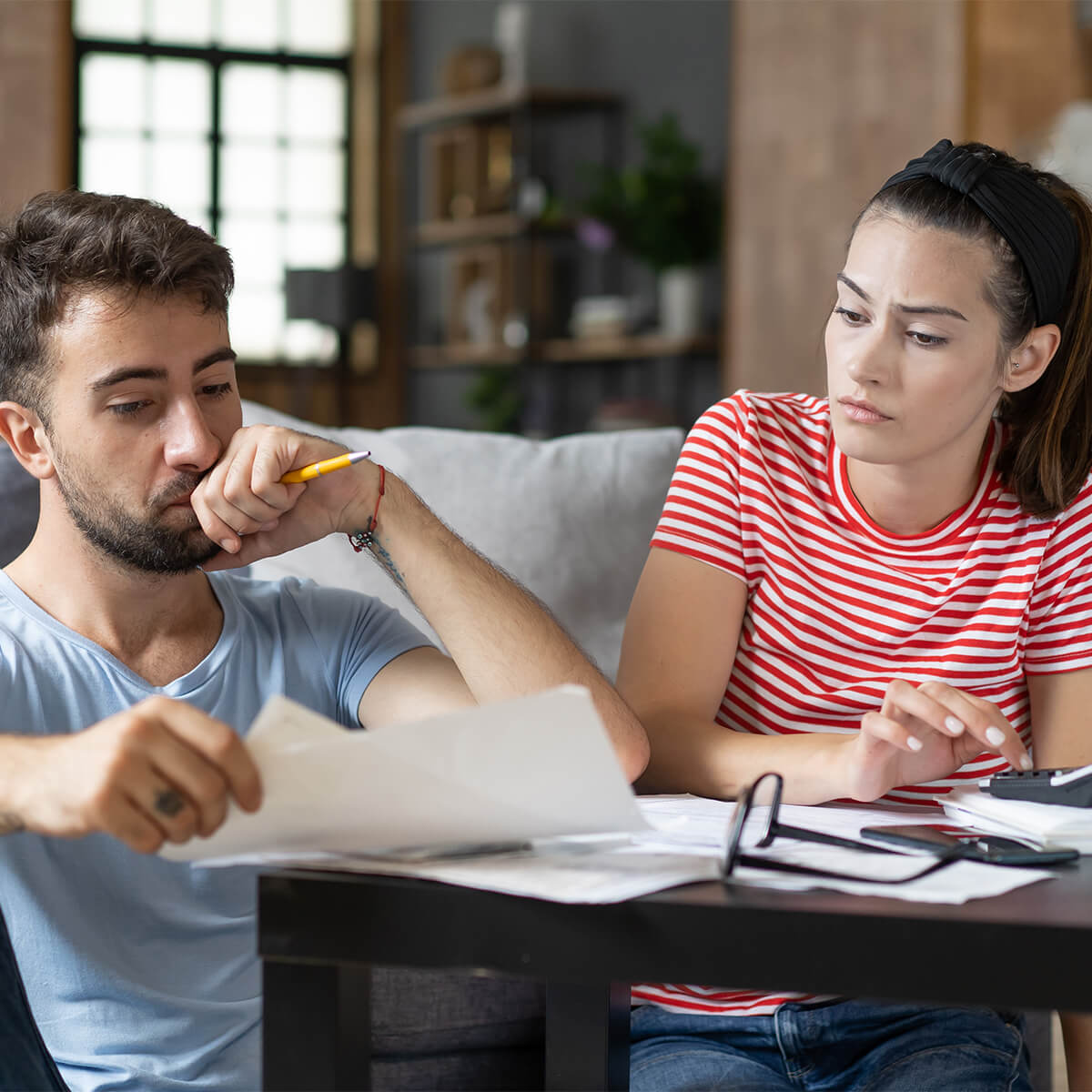 Frustrated concerned young couple calculating overspend budget