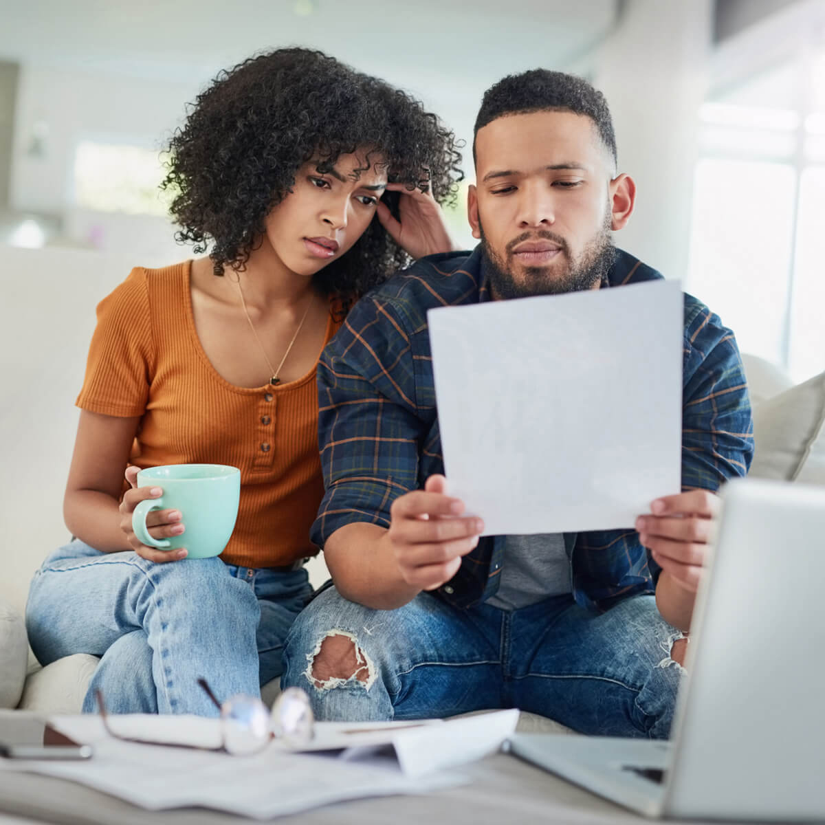 Un couple assis sur un canapé regardant ses factures