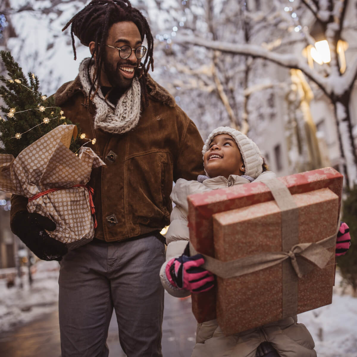 Un père et son fils marchent dans la rue les mains remplies de cadeaux